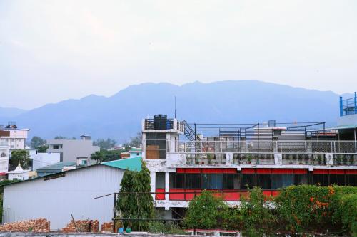 a building with a balcony with mountains in the background at Madhuban Homestay, Natraj Chowk in Rishīkesh