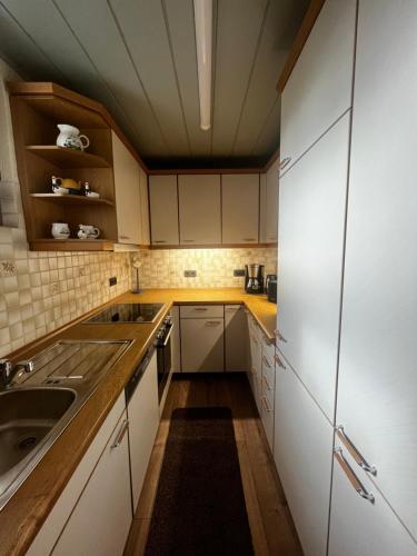 una cocina con armarios blancos y fregadero en Ferienwohnung Schneider en Baumholder