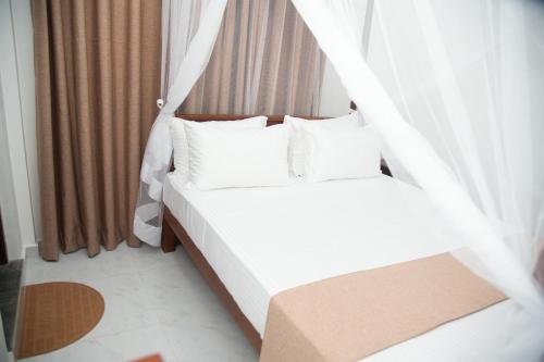 a bed with white sheets and pillows in a room at Tango Sunrise Villa in Tangalle
