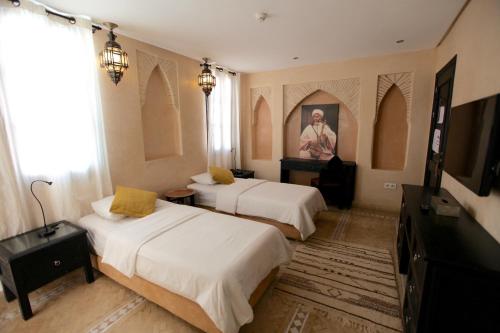 a hotel room with two beds and a television at Riad Dar Haven in Tamraght Ou Fella