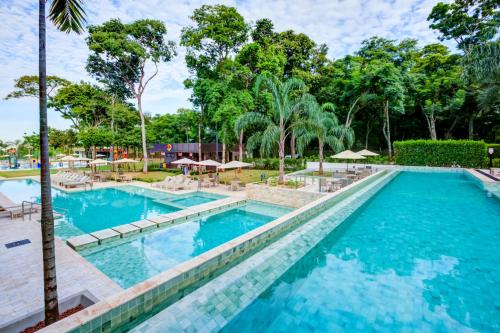 a pool with chairs and umbrellas at a resort at DoubleTree by Hilton - Resort - Foz do Iguaçu in Foz do Iguaçu