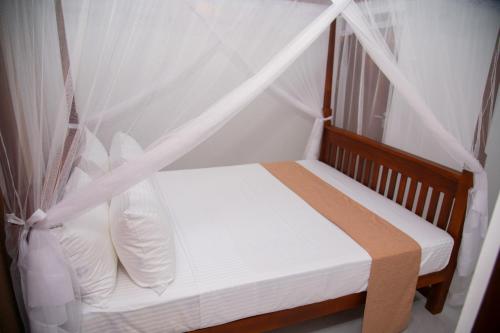 a bed with white sheets and a canopy at Tango Sunrise Villa in Tangalle