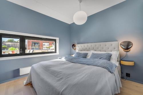 um quarto com uma cama com paredes azuis e uma janela em Beautifull apartment w 1 bedroom em Oslo