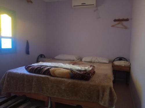 Un dormitorio con una cama con una manta. en auberge djebel rose 2, en Tafraoute