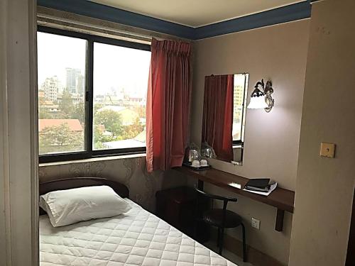 a bedroom with a bed and a desk and a window at RS Galaxy HOTEL in Phnom Penh