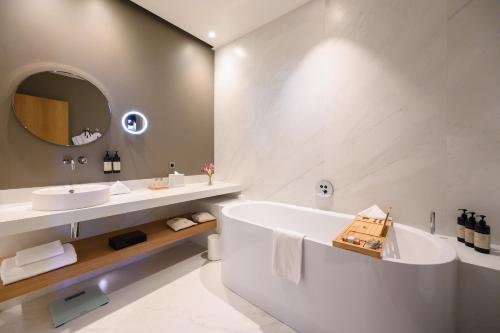 a bathroom with a tub and two sinks and a mirror at Domaine de la Reine Margot Paris-Issy - MGallery Collection in Issy-les-Moulineaux
