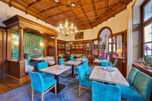 ガルミッシュ・パルテンキルヒェンにあるホテル アッシェンブレナーのテーブルと椅子、シャンデリアのあるレストラン