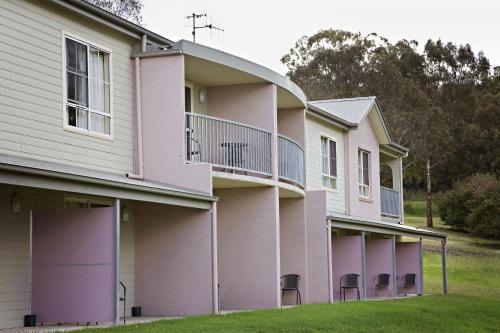 a building with pink paint and chairs in the grass at BATHURST GOLDFIELDS MOTEL at 428 CONROD STRAIGHT MOUNT PANORAMA in Bathurst
