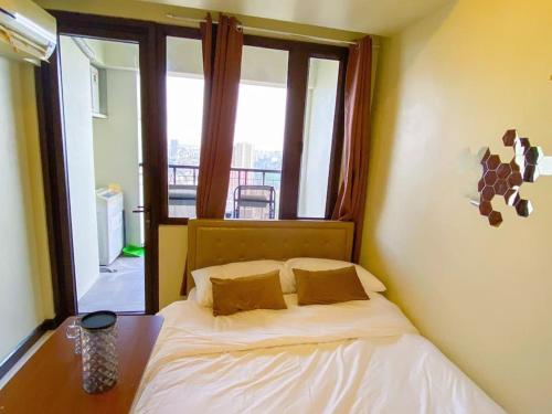 ein kleines Bett in einem Zimmer mit Fenster in der Unterkunft Hotel & Karaoke - Jianna's Place in Manila