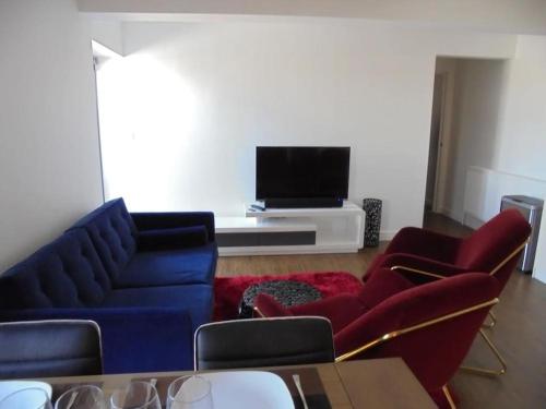 a living room with two blue couches and a tv at Beach Penthouse Apartment Bournemouth in Bournemouth