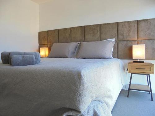 ein Schlafzimmer mit einem großen Bett und einem Tisch mit einer Lampe in der Unterkunft Beach Penthouse Apartment Bournemouth in Bournemouth