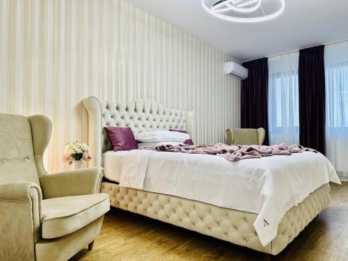 een slaapkamer met een groot bed en 2 stoelen bij Sky Garden Panoramic View in Boekarest