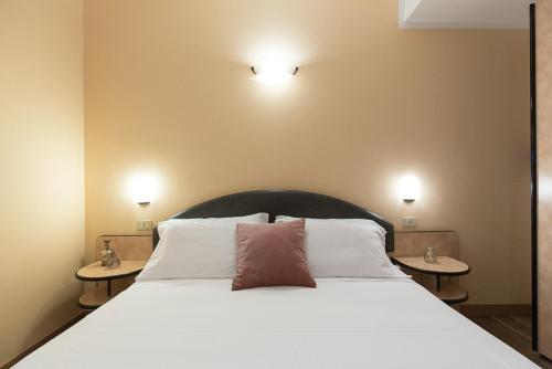 een slaapkamer met een groot wit bed en 2 tafels bij Hotel Trevi Riccione in Riccione