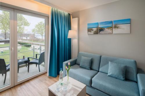 a living room with a blue couch and a large window at BeachSide in Eckernförde