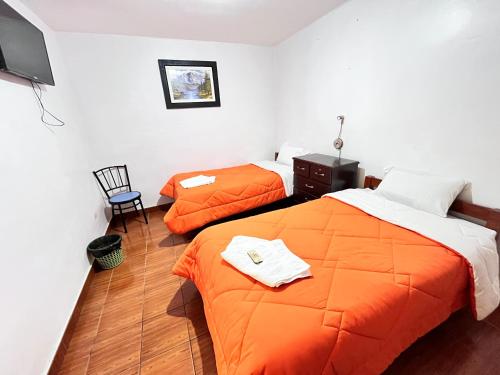 duas camas num quarto com lençóis laranja em Sunrise Guest House em Huaraz