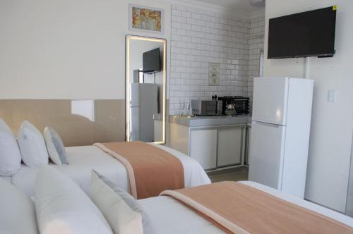 a hotel room with two beds and a refrigerator at Shark Island Guesthouse in Lüderitz