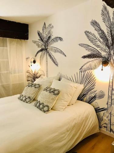 ein Schlafzimmer mit einem weißen Bett mit zwei Palmen an der Wand in der Unterkunft Au coeur du quartier historique in Montpellier