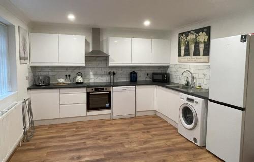 a kitchen with white cabinets and a washer and dryer at 1 Fitzhamon Embankment APARTMENTS opposite Principality Stadium - free parking nearby - LONG STAY OFFER - newly redecorated March 2024 in Cardiff