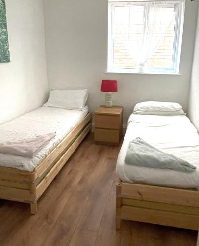 two twin beds in a room with a window at 1 Fitzhamon Embankment APARTMENTS opposite Principality Stadium - LONG STAY OFFER in Cardiff