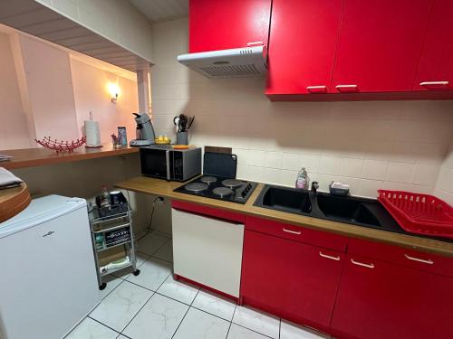 uma cozinha com armários vermelhos e um forno com placa de fogão em Spacieux studio confortable em Anzin