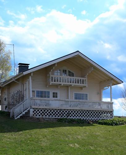 une grande maison blanche avec une terrasse couverte sur un champ dans l'établissement LAKESIDE COTTAGE Private beach, à Ikaalinen