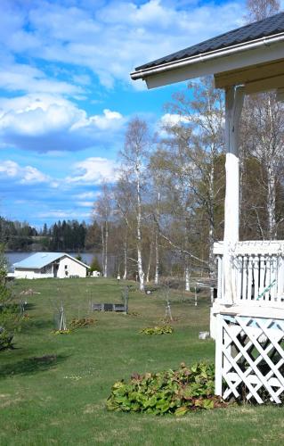 a white house with a fence and a yard at LAKESIDE COTTAGE Private beach in Ikaalinen
