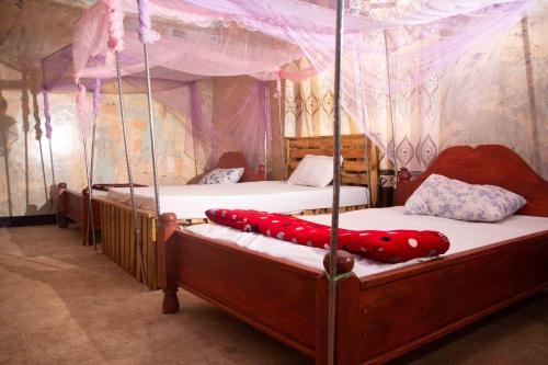 two beds in a bedroom with a canopy at Kilibase Hotel in Moshi