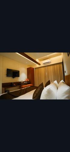 een hotelkamer met 2 bedden en een televisie bij M/s. Hari Govinda's Express in Mysore