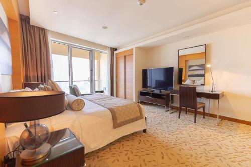 a hotel room with a bed and a desk and a television at Four Apple EMAAR Fashion Avenue Studio in Dubai