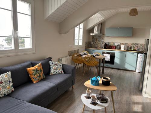 ein Wohnzimmer mit einem blauen Sofa und einer Küche in der Unterkunft Appartement pour évasion marine à Hauteville sur mer in Hauteville-sur-Mer
