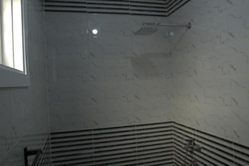 a bathroom with a white tile wall and a shower at Mogran Guest House in Luxor