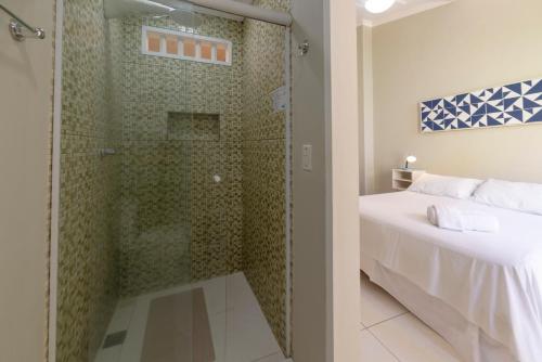 a bathroom with a shower and a bed in a room at Pousada Vila do Porto in Paraty