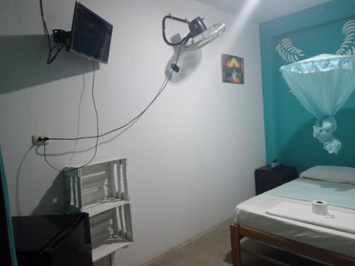 a room with a bed and a tv on a wall at La posada del amor in Máncora