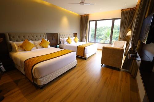 a hotel room with two beds and a window at The Aurum Subrahmanya in Subrahmanya