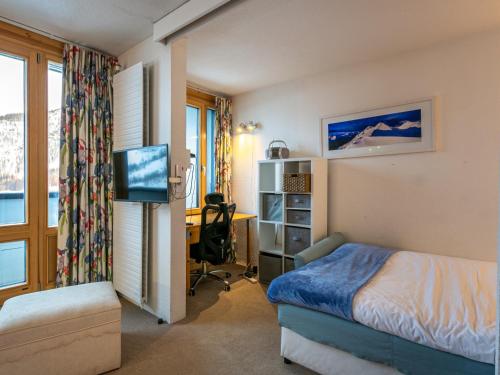 une chambre avec un lit et un bureau avec une télévision dans l'établissement Appartement skis aux pieds avec parking, wifi, animaux admis à Val-d'Isère - FR-1-694-238, à Val dʼIsère