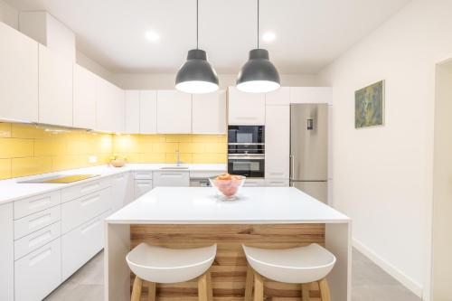 a kitchen with white cabinets and a island with two stools at La Cochera Casa Emblemática en Santa Cruz de Tenerife in Santa Cruz de Tenerife