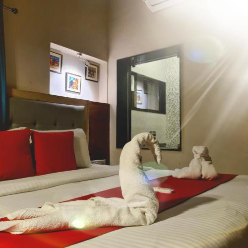 a bedroom with two beds with a towel animal on the floor at EMINENCE - PALM RESIDENCY (1.5 KM FROM NAKKI LAKE) in Mount Ābu
