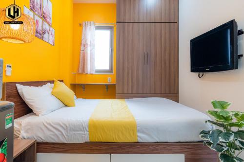 a bedroom with a bed with yellow walls and a tv at Luxury Condotel Sai Gon 2 in Ho Chi Minh City
