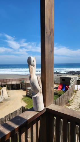 a statue of a seal sitting on a balcony overlooking the beach at Espectacular Casa Palafito frente al mar in Pichilemu