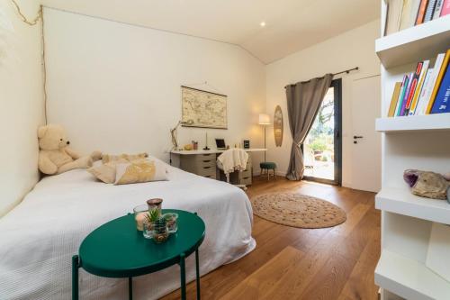 een slaapkamer met een wit bed en een groene tafel bij VILLA au Bord du Lac de Sanguinet in Sanguinet