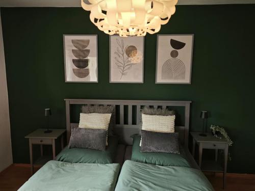 a green bedroom with two beds and a chandelier at 3 Zimmer Ferienwohnung 80qm in Bamberg