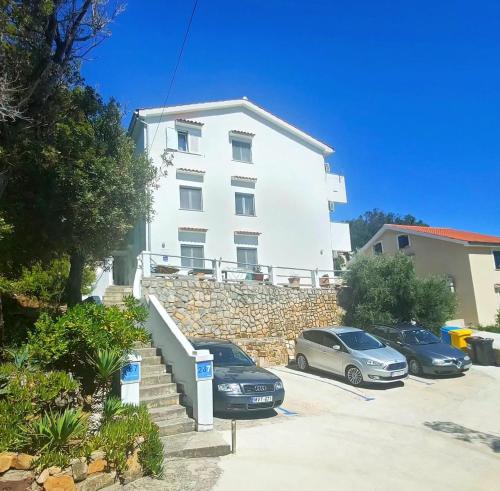 un edificio blanco con coches estacionados en un estacionamiento en Rab Island Apartments Del Sole, en Supetarska Draga