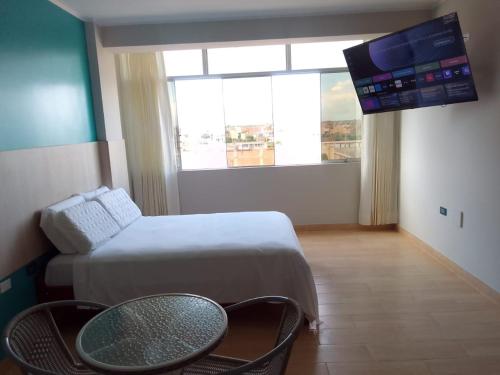 Habitación con cama, mesa y TV. en Hostal Tulipán Rojo, en Lambayeque