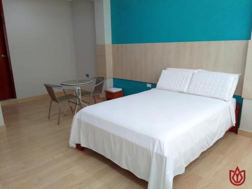1 dormitorio con cama blanca y mesa en Hostal Tulipán Rojo, en Lambayeque