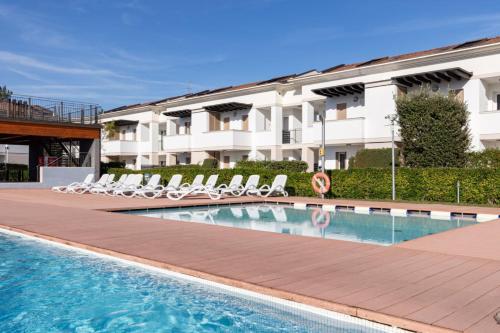 una piscina con sedie a sdraio e un edificio di Villaggio Evanike a Bibione