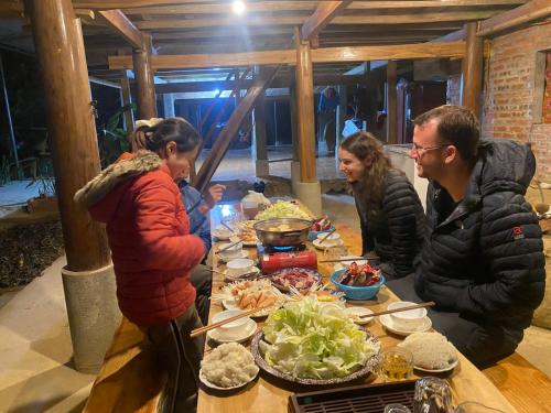 un grupo de personas de pie alrededor de una mesa con comida en Puluong Aroma, en Hương Bá Thước