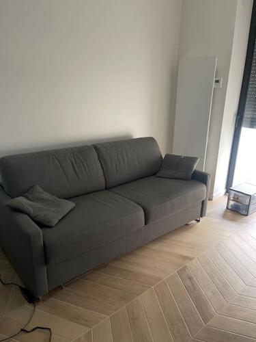 a gray couch in a living room with a wooden floor at Pavillon sur cour . in Paris