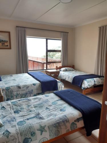 a hotel room with three beds and a window at Berg En See in Kleinmond