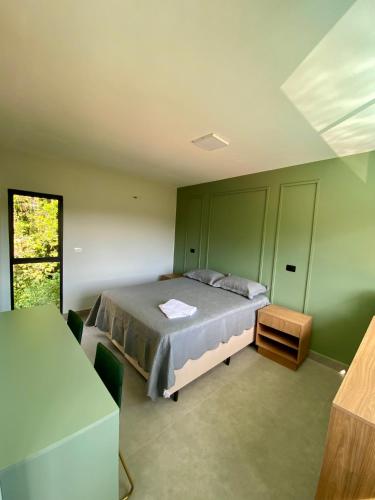 Un dormitorio con una cama en una habitación con paredes verdes. en Suítes Por do Sol, en Cabreúva