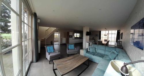 a living room with a blue couch and a table at Wilgenwind in Sijsele